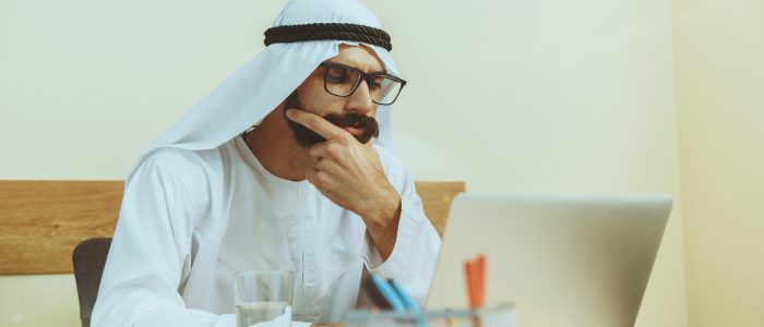 Arab saudi businessman working online with a laptop and tablet in his comfortable cabinet or office. Male model as an enterpreneur. Concept of business, finance, modern technologies, start up, economy.